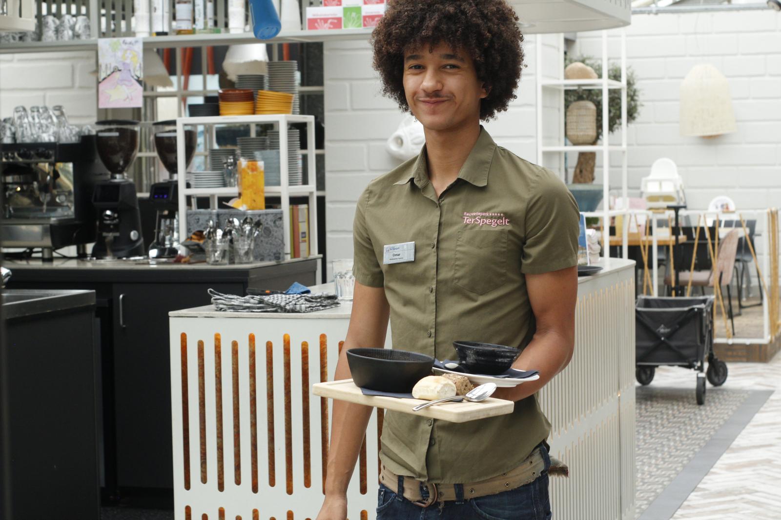 Medewerker in de bediening brengt een dienblad met soep en brood naar een gast