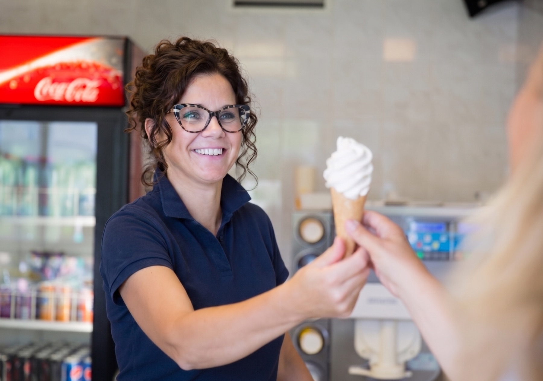Medewerker geeft een gast met een glimlach een ijsje aan